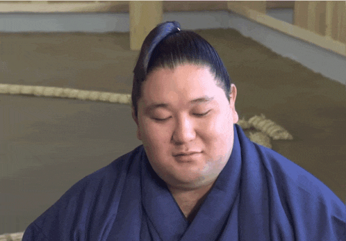 a sumo wrestler with his eyes closed wearing a blue kimono