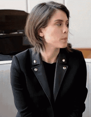 a woman wearing a black leather jacket is sitting down