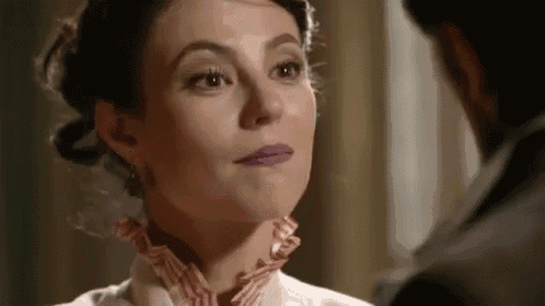 a woman with purple lipstick on her lips is looking at a man in a suit .