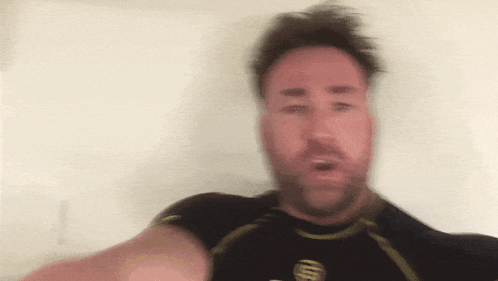 a man with a beard is wearing a black shirt with an at & t logo on the front