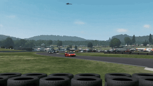 a helicopter is flying over a race track with a red car on it