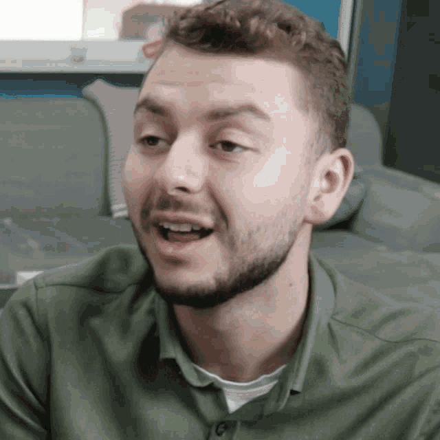 a man with a beard is wearing a green shirt and white undershirt