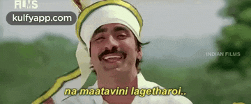 a man with a mustache and a bandana on his head is smiling and saying na maatavini lagetharoi .