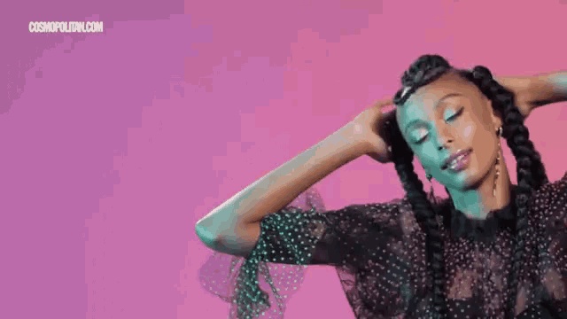a woman in a polka dot dress is holding her hair in braids .