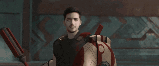 a man in a spartan costume holds a spear and shield in his hands
