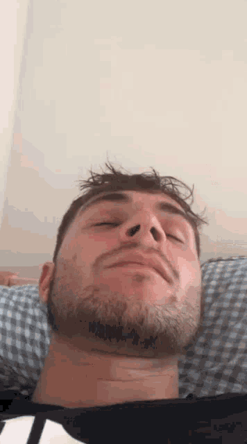 a man with a beard is laying down with his eyes closed .