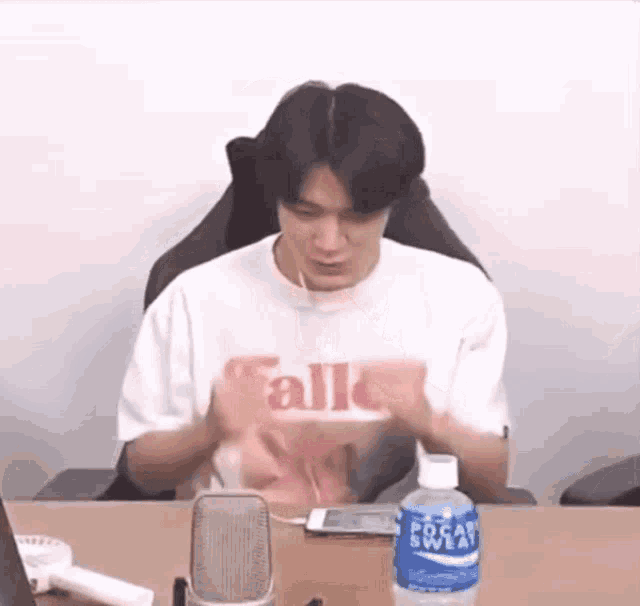 a man is sitting at a table with a bottle of pocari sweat next to him .