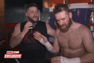 a man talking into a microphone with a wwe.com exclusive sticker on the bottom