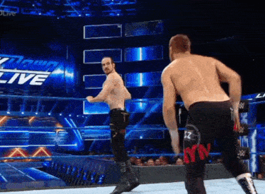 two wrestlers in a wrestling ring with the word live on the wall behind them
