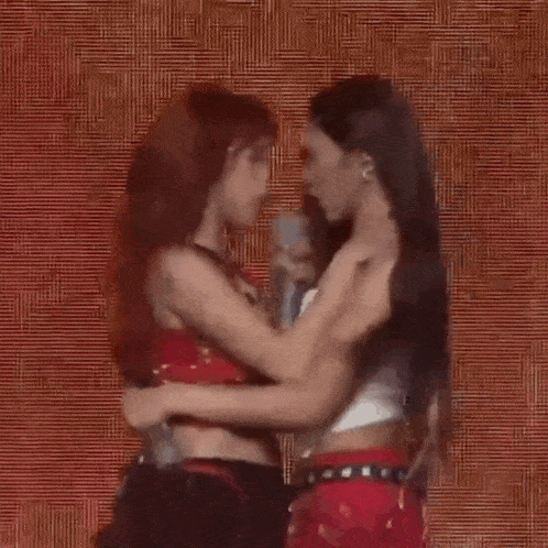 a couple of women are hugging each other on a stage .