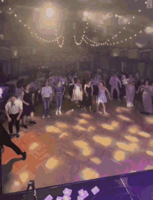 a group of people are dancing in a large room