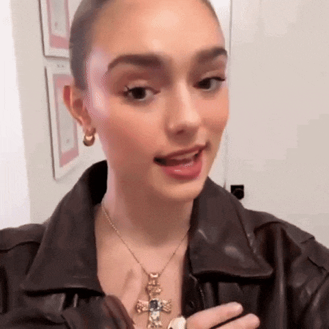 a woman wearing a brown leather jacket and a necklace with a cross pendant .