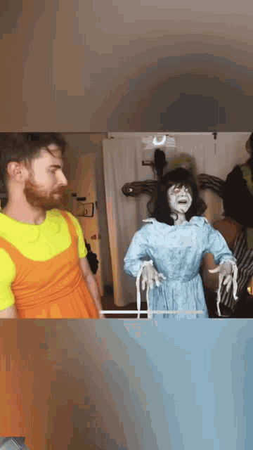 a man in an orange dress is standing next to a ghost statue