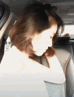 a woman is sitting in the back seat of a car and looking down .