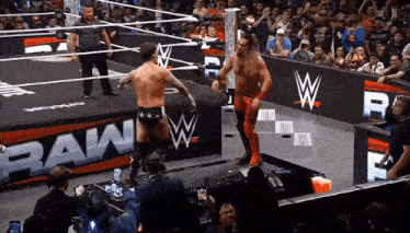 two wrestlers are standing in a wrestling ring with a sign that says raw