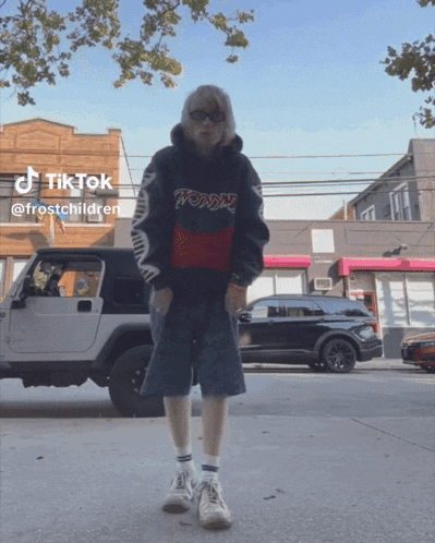 a person wearing a tommy hilfiger hoodie is standing on a sidewalk