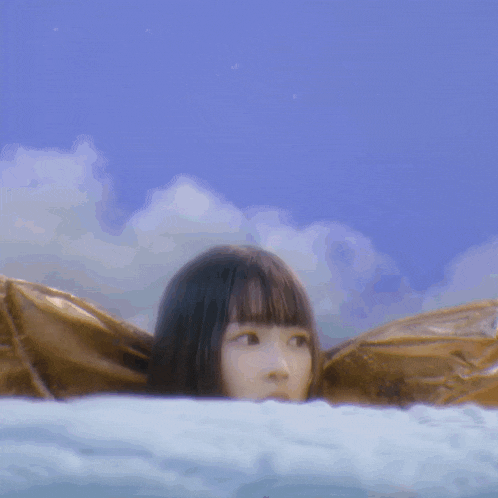 a young girl is laying on a bed with a blue sky in the background
