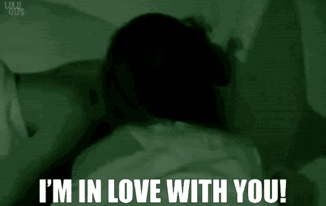 a man and woman are kissing in a dark room with the words i 'm in love with you .
