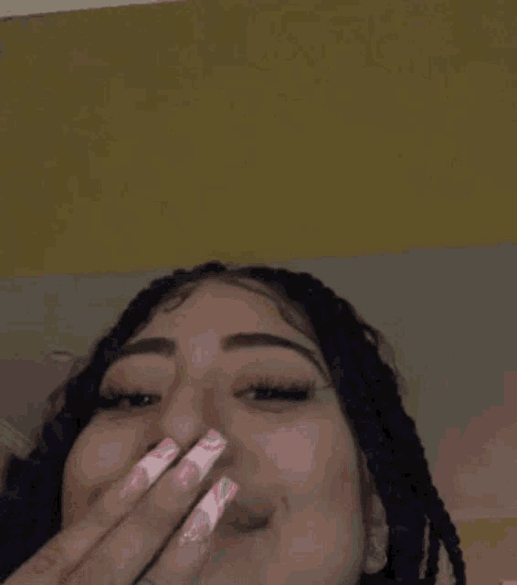 a close up of a woman covering her mouth with her hand .