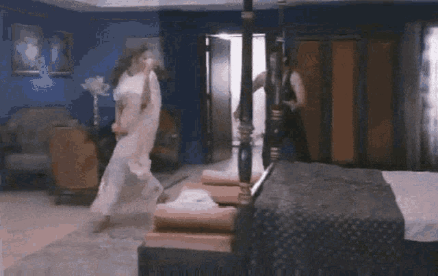 a man and woman are dancing in a bedroom next to a four poster bed