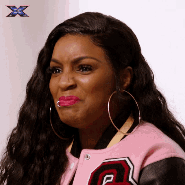 a woman wearing hoop earrings and a pink jacket with the letter p on it