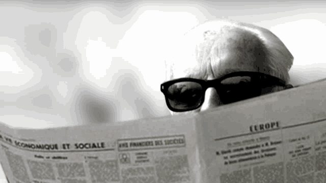 a man wearing sunglasses is reading a newspaper with europe written on it
