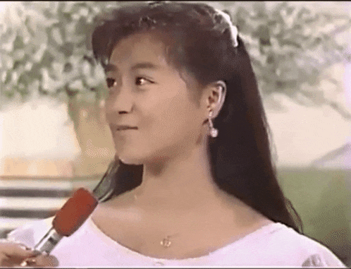 a woman is talking into a microphone while wearing earrings .