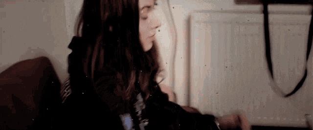 a woman is sitting on a couch in front of a radiator looking at something .