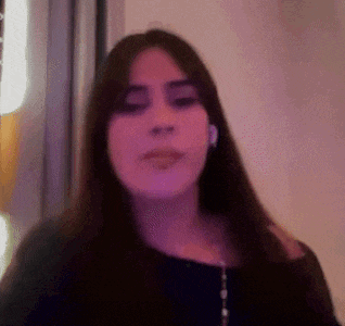 a woman with long dark hair is wearing a black shirt and earrings