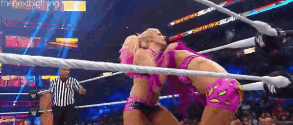 two women are wrestling in a wrestling ring with a referee watching .