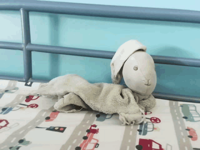a stuffed animal is laying on a bed with cars on the sheets