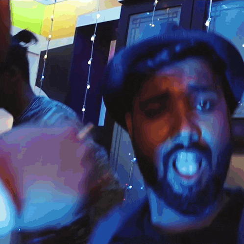 a man with a beard wearing a hat and making a funny face