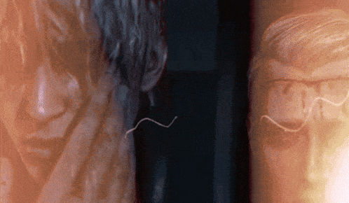 a close up of a man 's face with glasses and a worm coming out of it