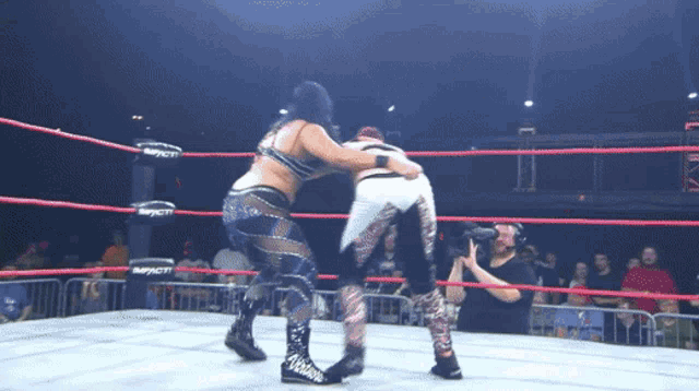 two women wrestling in a ring with the word impact on the ropes