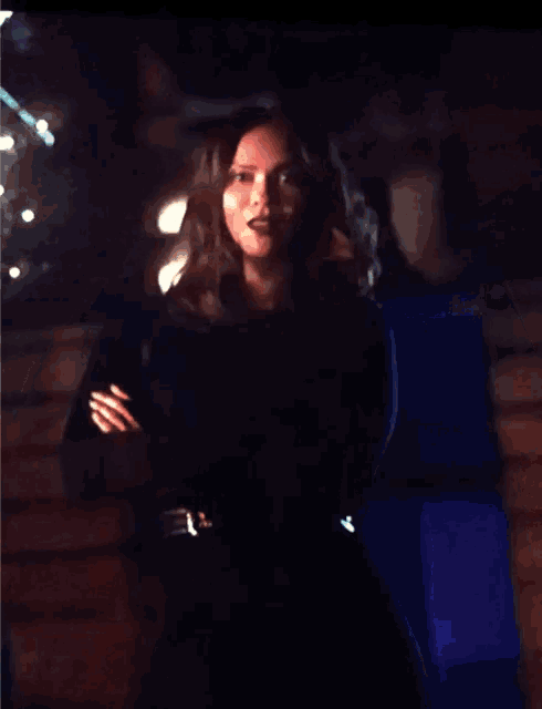 a woman in a black dress is making a funny face with her hands in the air