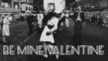 a black and white photo of a man and woman kissing on a street with the words `` be mine valentine '' .