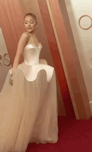 a woman is standing on a red carpet wearing a white dress .