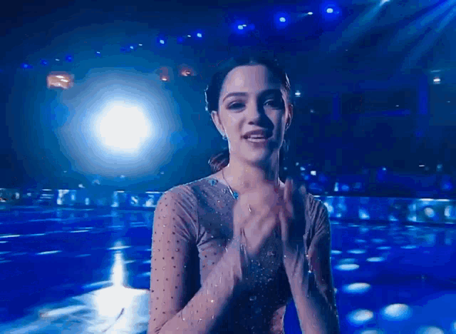 a woman is covering her mouth with her hands in front of a blue background