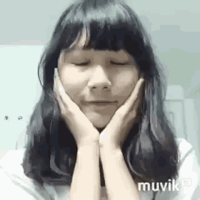 a young woman with her hands on her face is smiling .