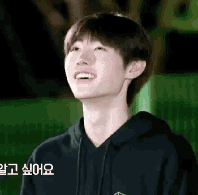 a young man wearing a black hoodie is smiling and looking up at the sky .