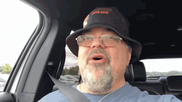 a man in a car wearing a hat that says ' supreme ' on the front