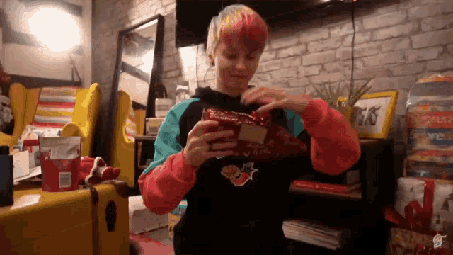 a person with pink hair is opening a gift with a sticker that says ' supreme ' on it