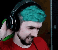 a man with green hair wearing headphones and a red shirt .