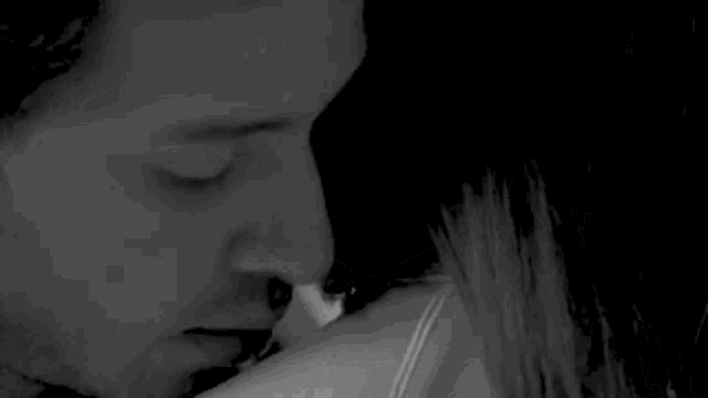 a black and white photo of a man and woman kissing .