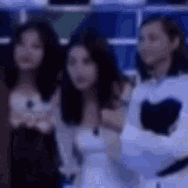 a group of three women are standing next to each other in a dark room .