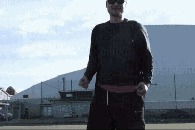 a man wearing sunglasses stands in front of a building