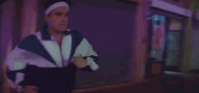 a man wearing a headband is running in a dark room with a pepsi machine in the background .