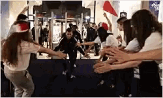 a group of people are dancing in a room with their arms outstretched .
