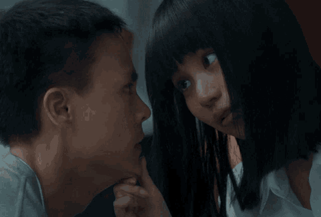 a man and a girl are looking at each other and the girl is touching the man 's face