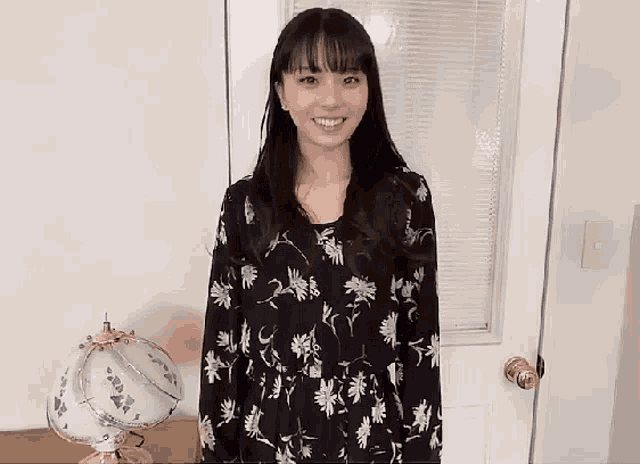 a woman in a floral dress is smiling in front of a door